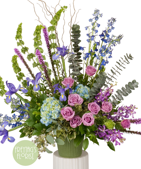 Sympathy arrangement of blue hydrangea, lavender roses, purple orchids and more.